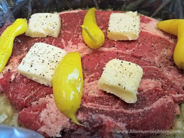Uncooked roast with pats of butter and peppers.