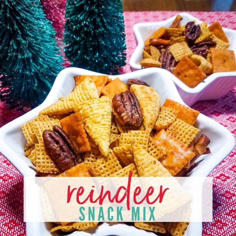 Close-up view of white star-shaped bowl filled with Reindeer Snack Mix (corn chex, cheese crackers, pretzels, Bugles & pecans) on a red tablecloth. | A Reinvented Mom