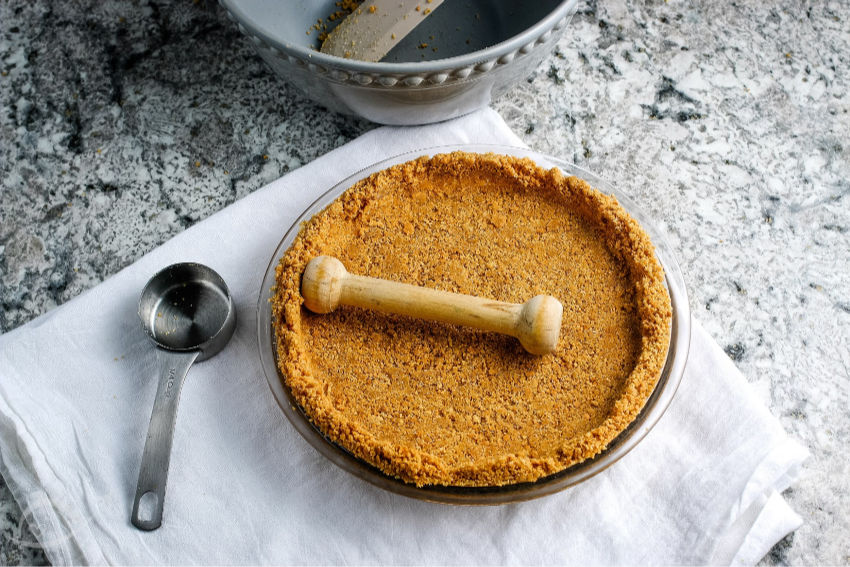 Graham Cracker Crust on a white towel with baking supplies. | A Reinvented Mom