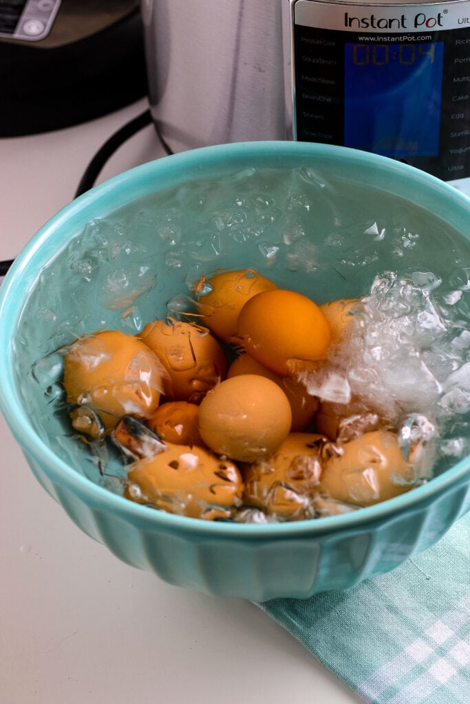 Blue bowl filled with ice & Instant Pot Hard Boiled Eggs on a napkin | A Reinvented Mom