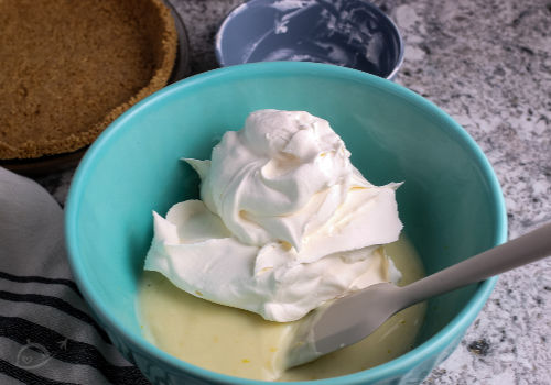 Lemonade pie filling & whipped cream in a blue bowl | A Reinvented mom