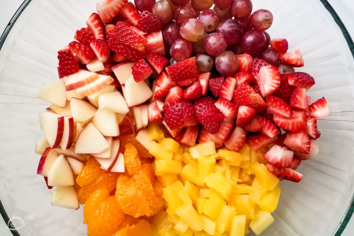 top view of all of the fruits for fruit cocktail salad in a glass bowl