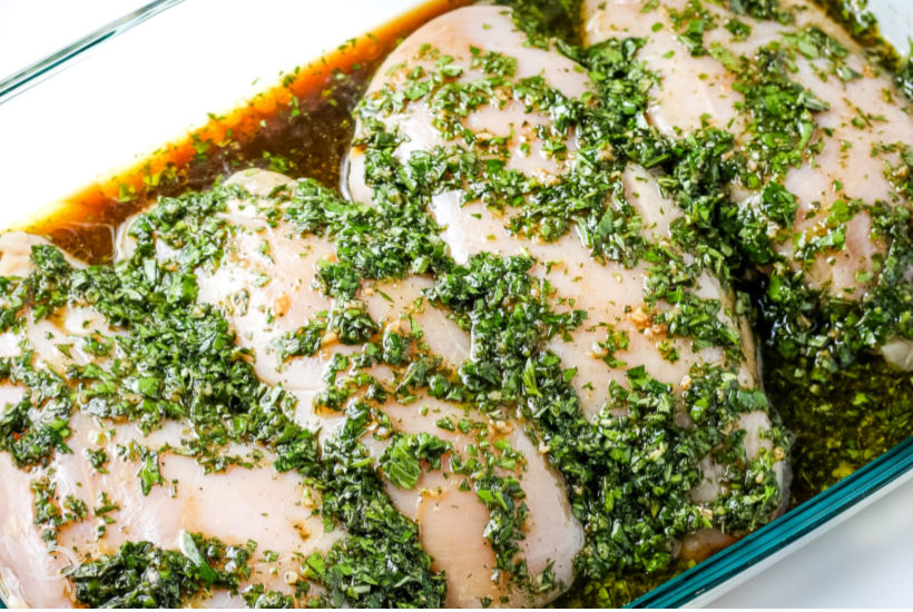 grilled chicken marinating in a glass dish with oil and herbs before grilling 