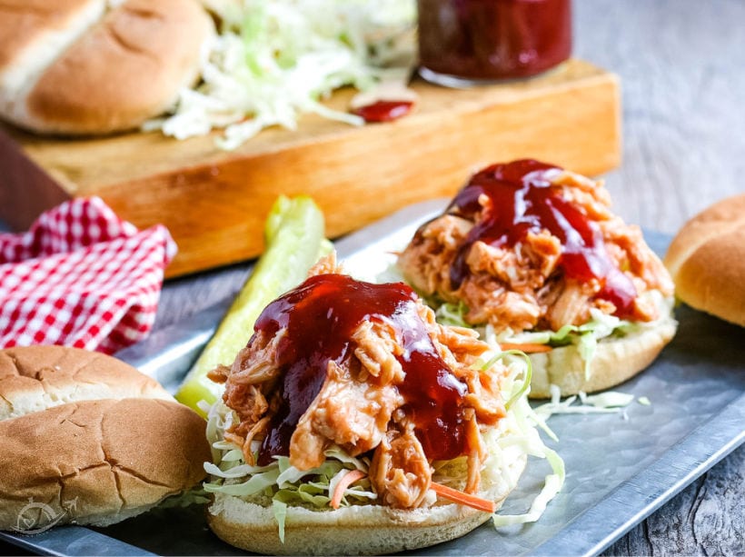 Crockpot bbq chicken shredded on a bun topped with bbq sauce next to a pickle