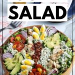 Chicken Cobb salad in a wooden serving bowl on a white marble background with graphic overlay.