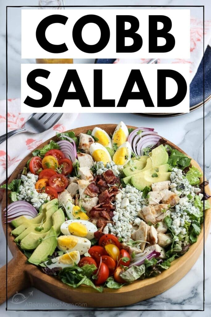 Chicken Cobb salad in a wooden serving bowl on a white marble counter top with graphic overlay.