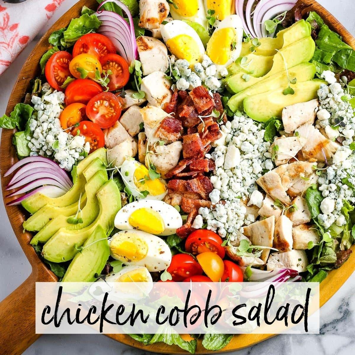 Chicken Cobb salad in a wooden serving bowl with graphic overlay.