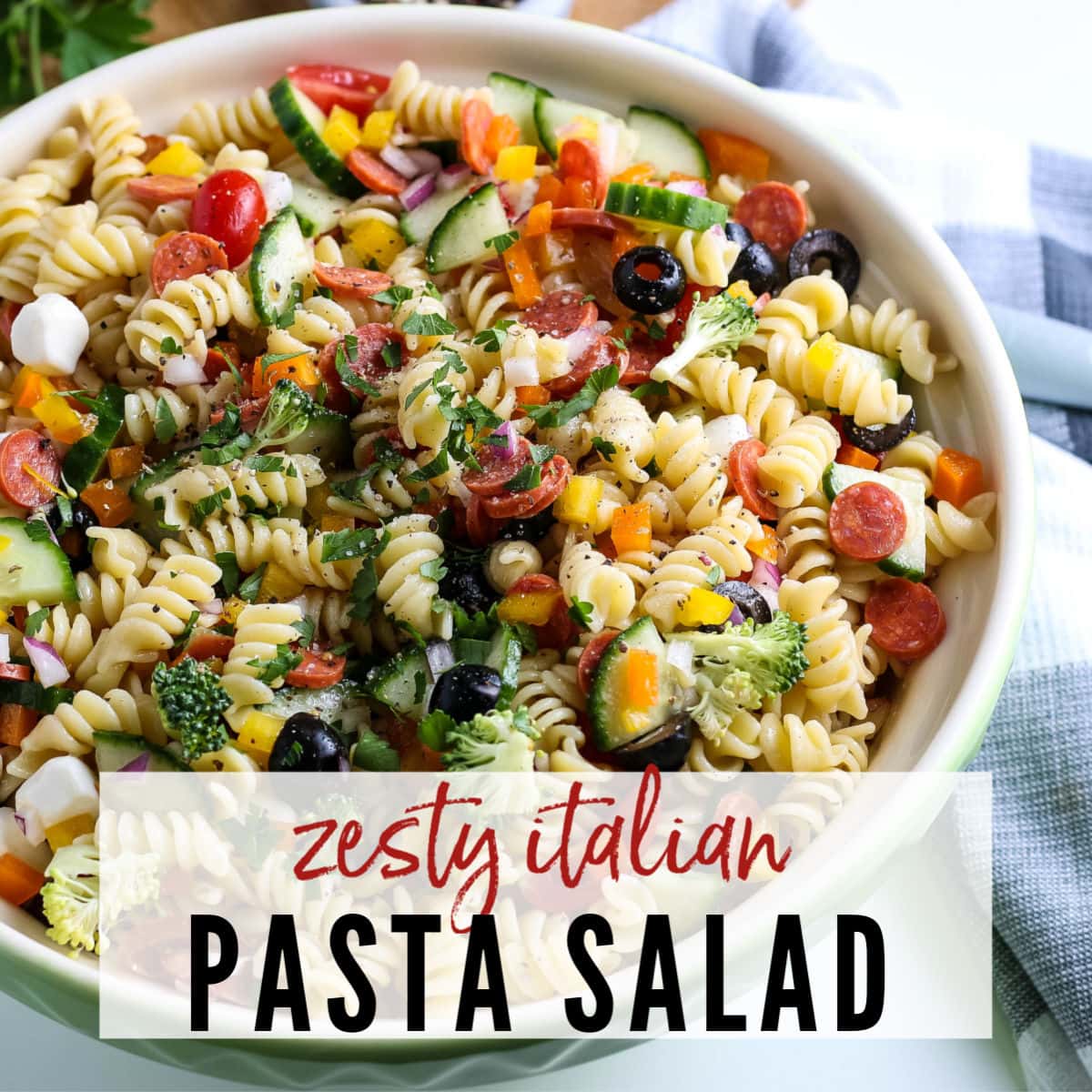 White bowl filled with pasta salad with fresh veggies, cheese & pepperoni