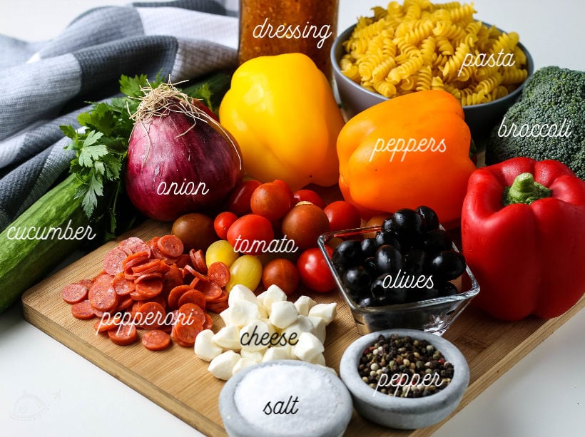 All the ingredients needed for zesty italian pasta salad on a cutting board