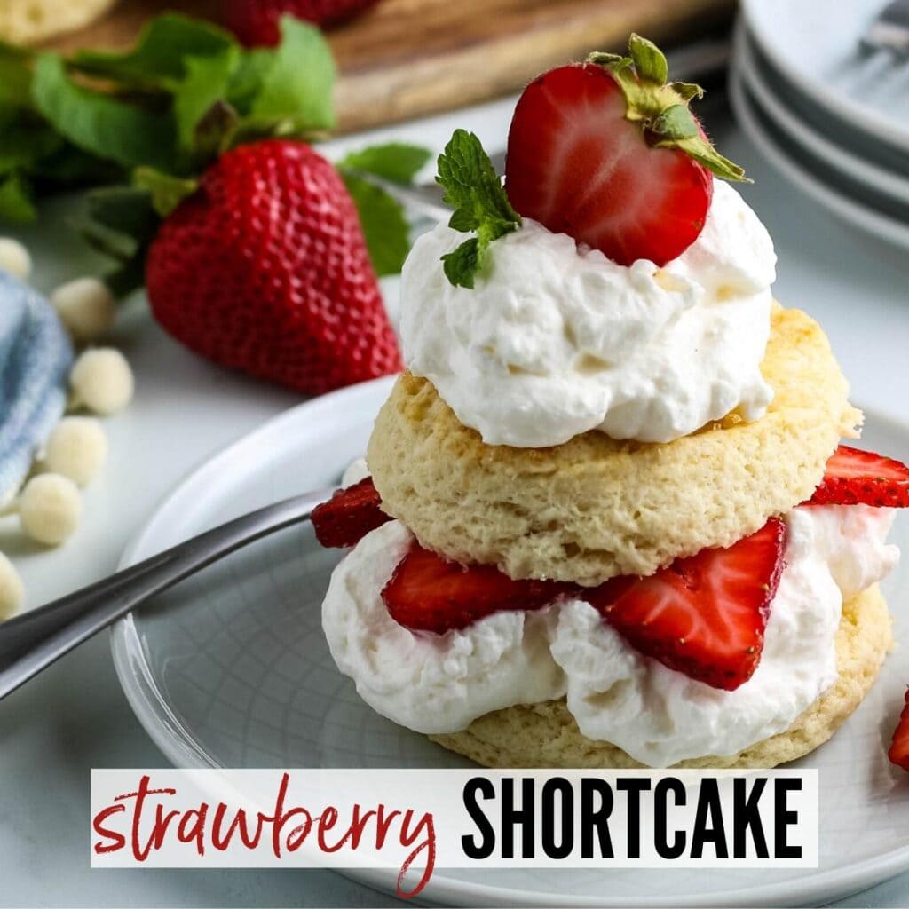 Sliced homemade biscuit with whipped cream & strawberries on a white plate with Strawberry Shortcake graphic | A Reinvented Mom