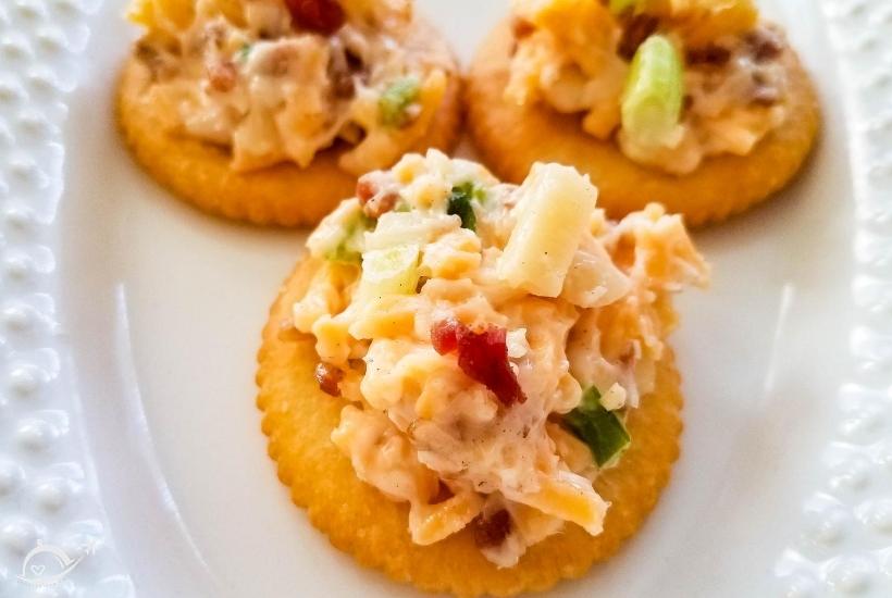 close up of 3 crackers with neiman marcus dip on them on a white plate