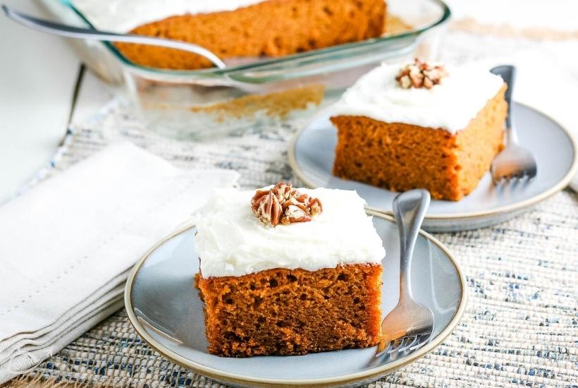 2 cake squares on blue plates with fork, pumpkin cake in casserole dish in the background