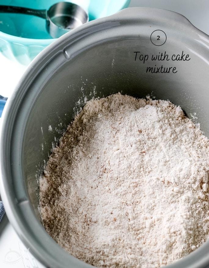 top view of cake mix over top of apple pie filling in a crockpot