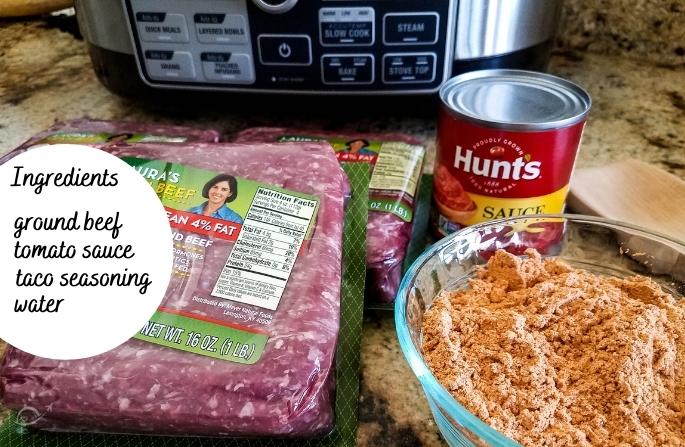 Ground beef, tomato sauce & taco seasoning ingredients on brown counter top.