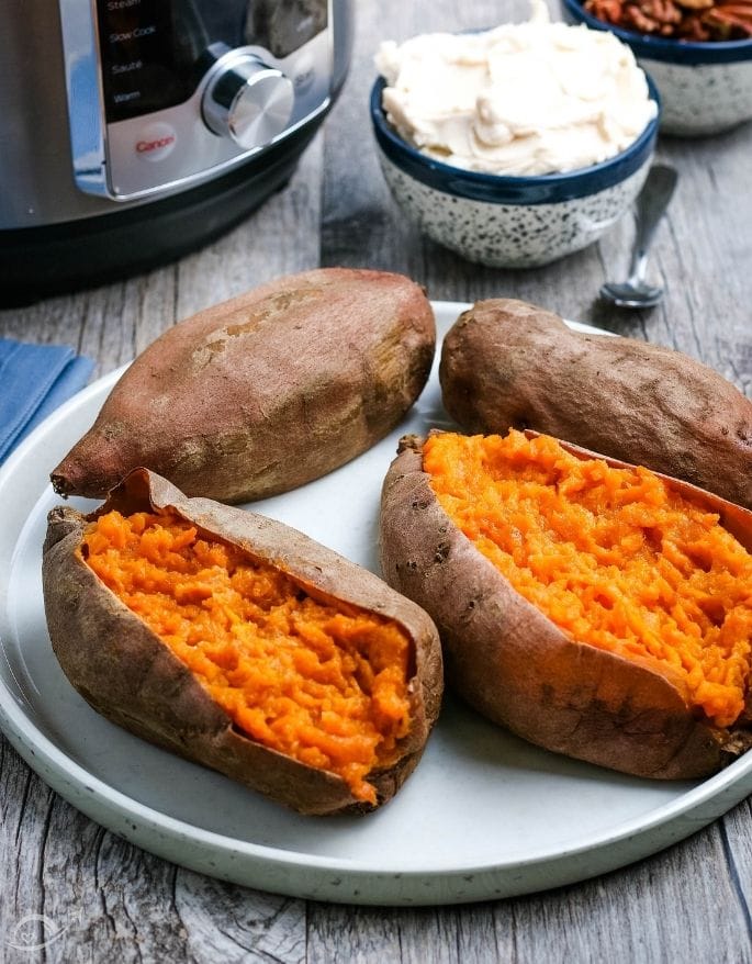 Baked sweet potatoes after cooking next to butter on a white plate