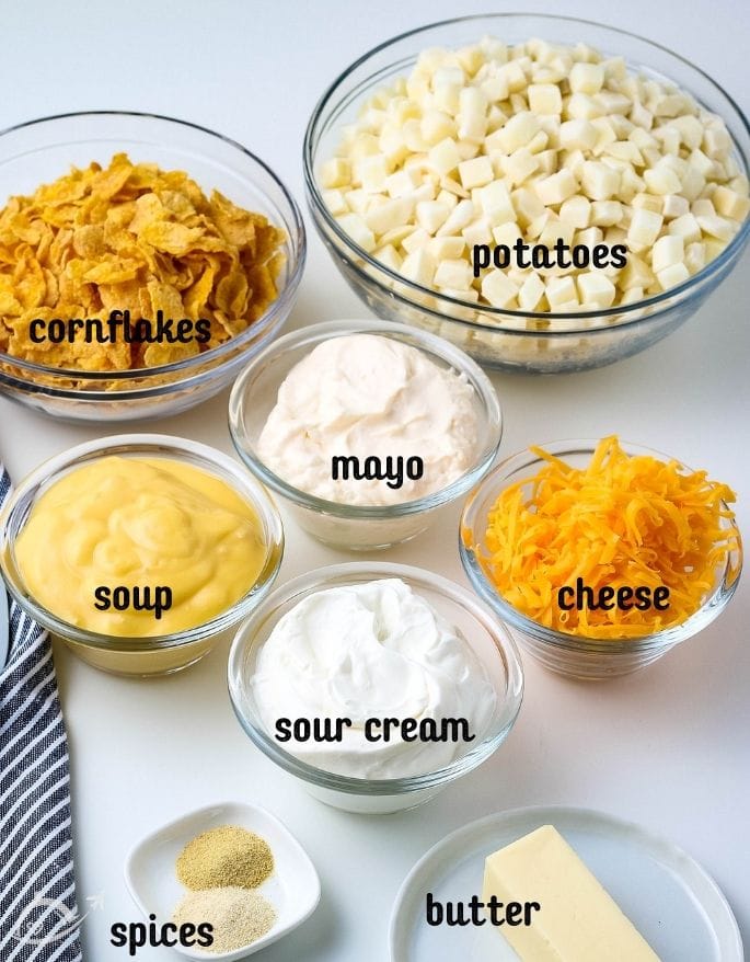 all of the ingredients for cornflake hashbrown casserole in glass bowls on white countertop