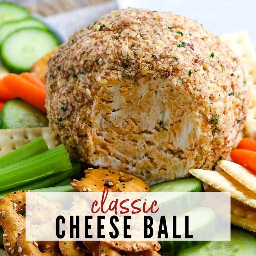 Close up of a cheese ball rolled in pecans next to veggies and crackers.