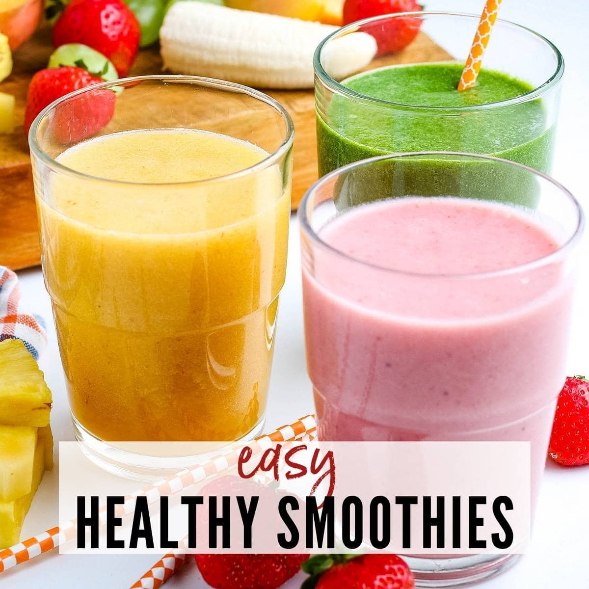 Three glasses of smoothies with fruit in the background