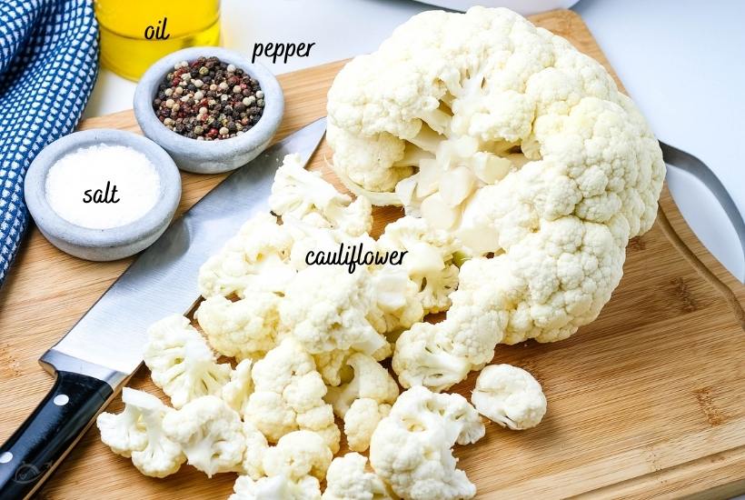 ingredients for air frying cauliflower labeled on a wooden cutting board