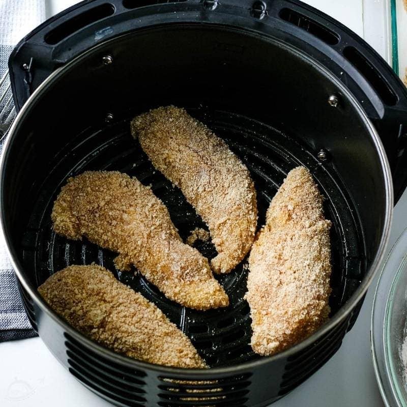 top view of breaded chicken tenders in an air fryer basket