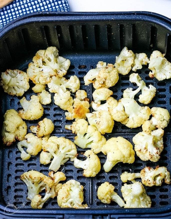 top view of cauliflower in an air fryer basket after cooking