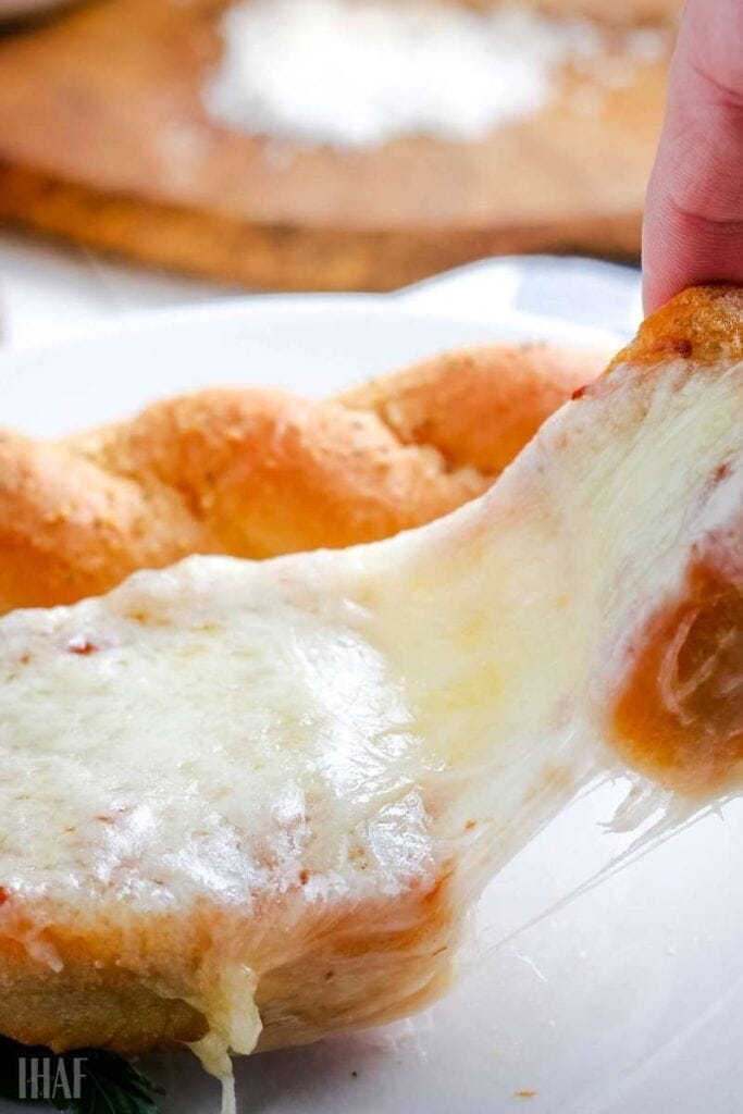 Showing the gooey and stringy cheese pull on the French bread pizza in air fryer.