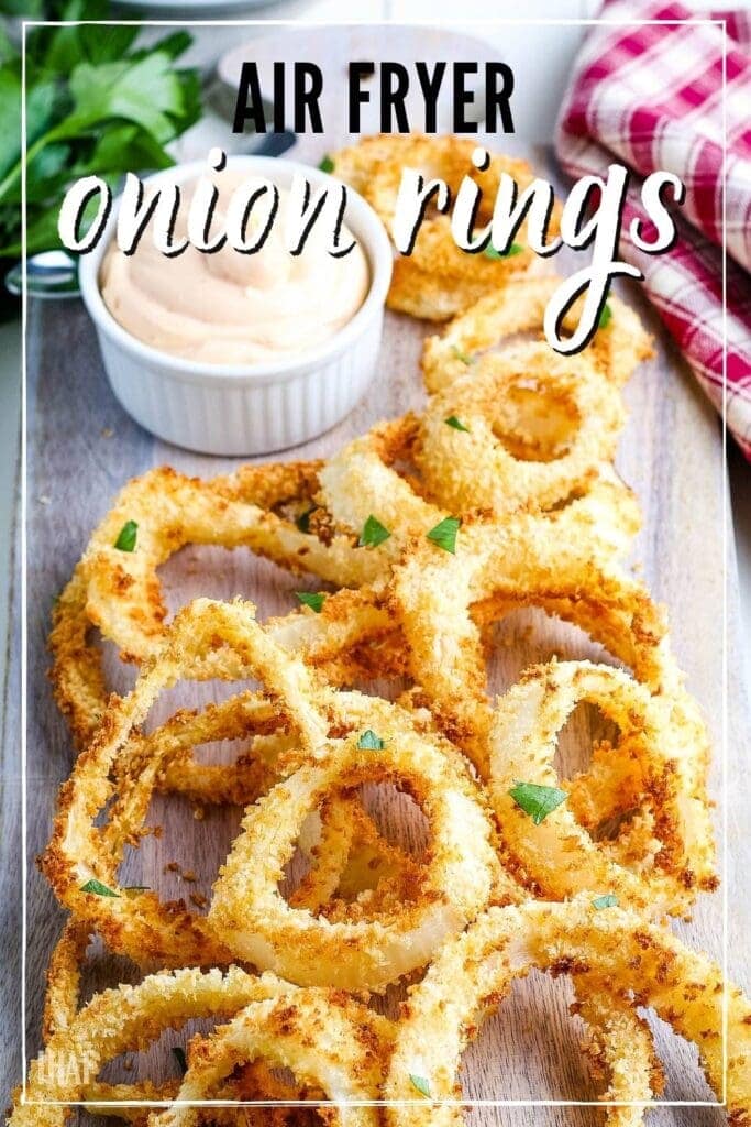 close up of air fried onion rings on a board with a ramekin of sauce and text overlay
