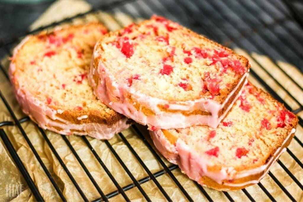 three slices of cherry bread on a wire rack topped with a cherry glaze