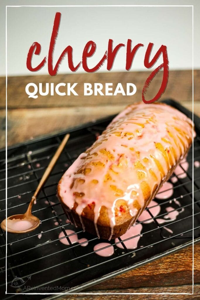 a loaf of cherry bread topped with glaze on a wire rack next to a spoon with text overlay
