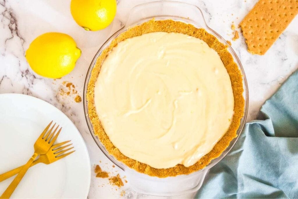 top view of lemon icebox cake in graham cracker crust next to lemons