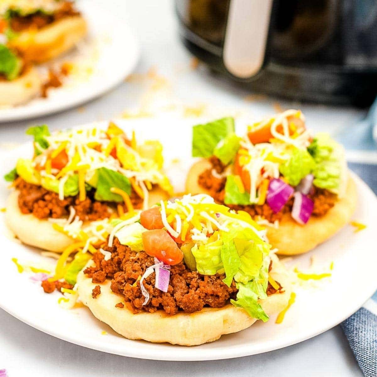 three air fryer navajo tacos with toppings on a white plate
