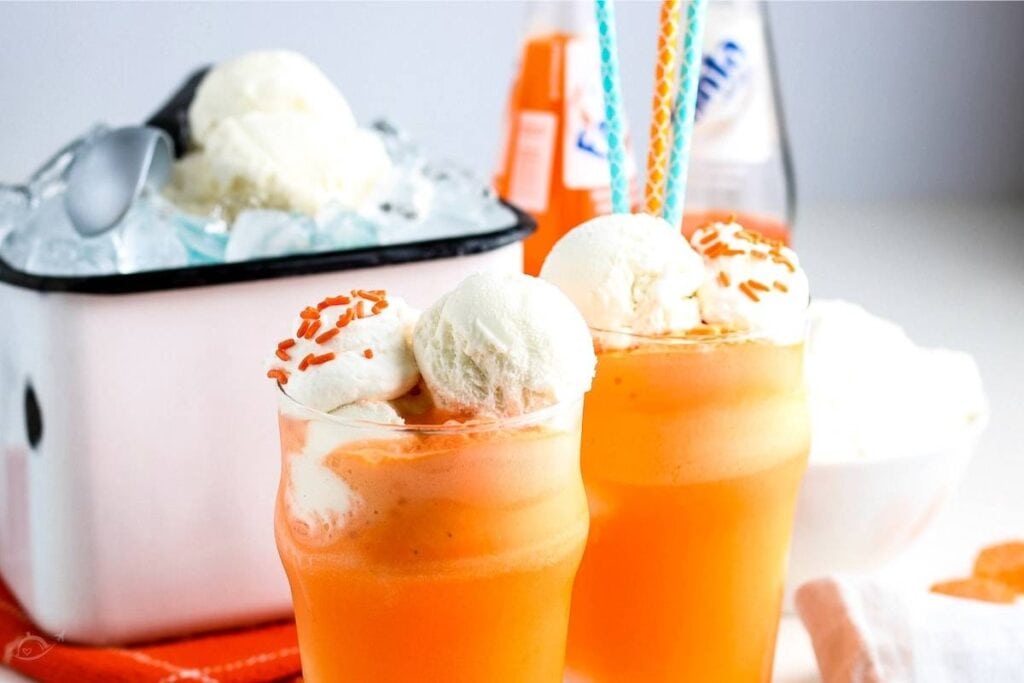 two orange floats next to ice cream bucket