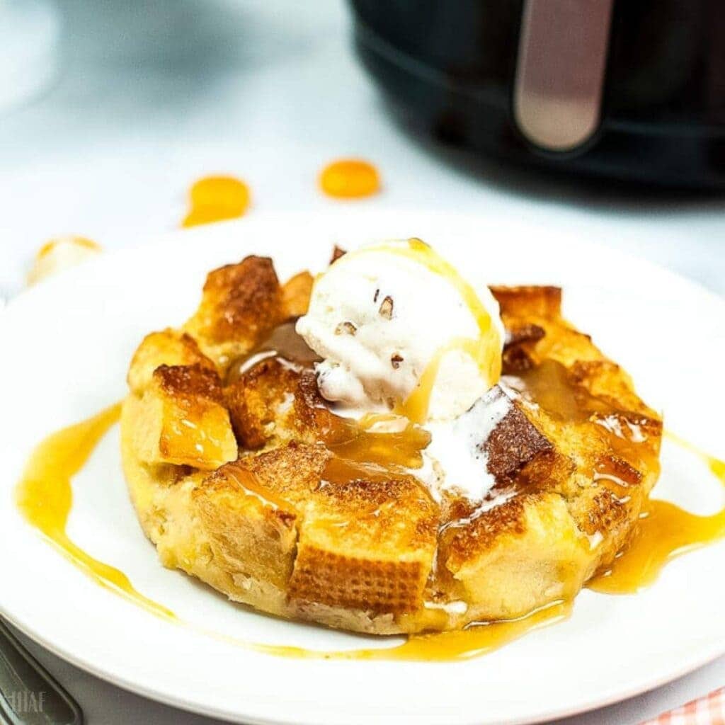 air fried bread pudding on a white plate topped with sauce and ice cream