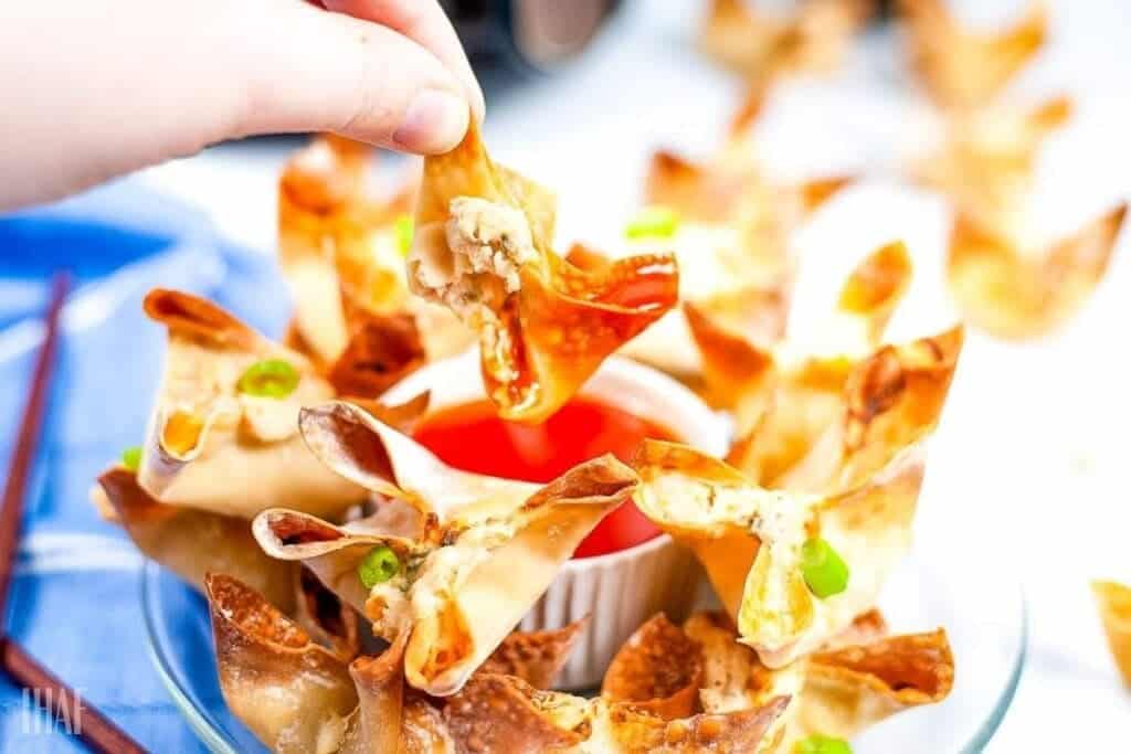 dipping an air fried crab rangoon in sauce