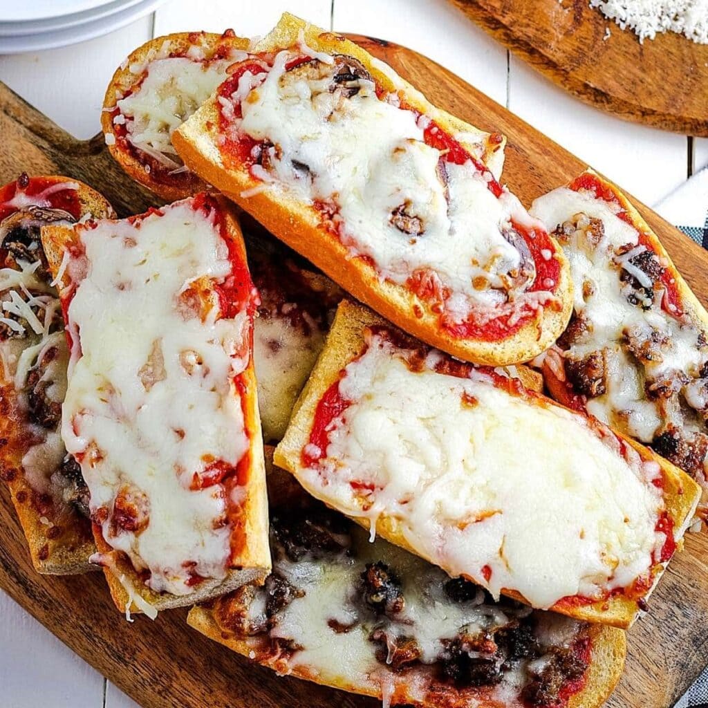 Air fryer pizza bread stacked on a wooden cutting board.