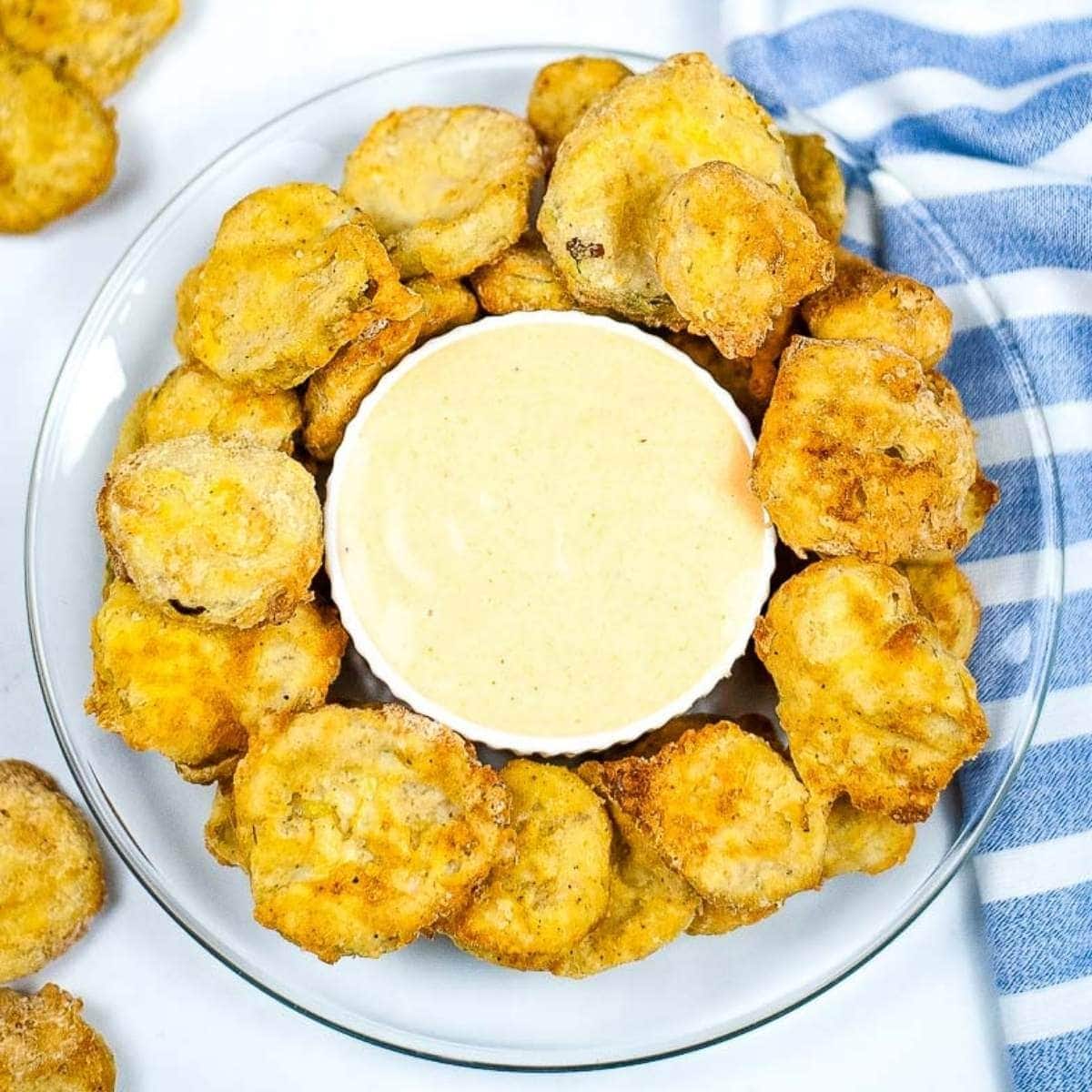 Top view of fried pickles on glass plate with sauce fresh out of the air fryer.