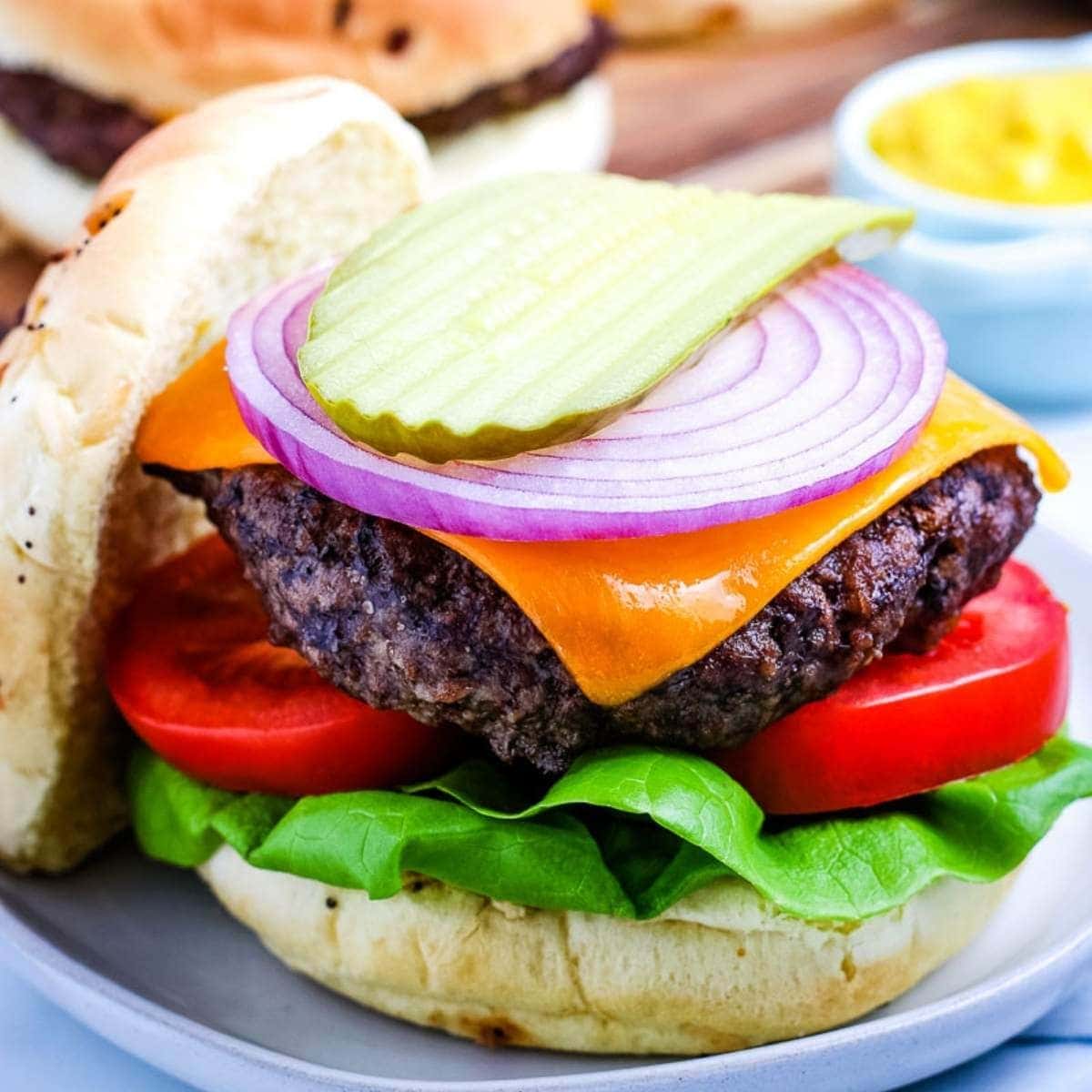 air fryer hamburger topped with cheese onion tomato lettuce and pickles