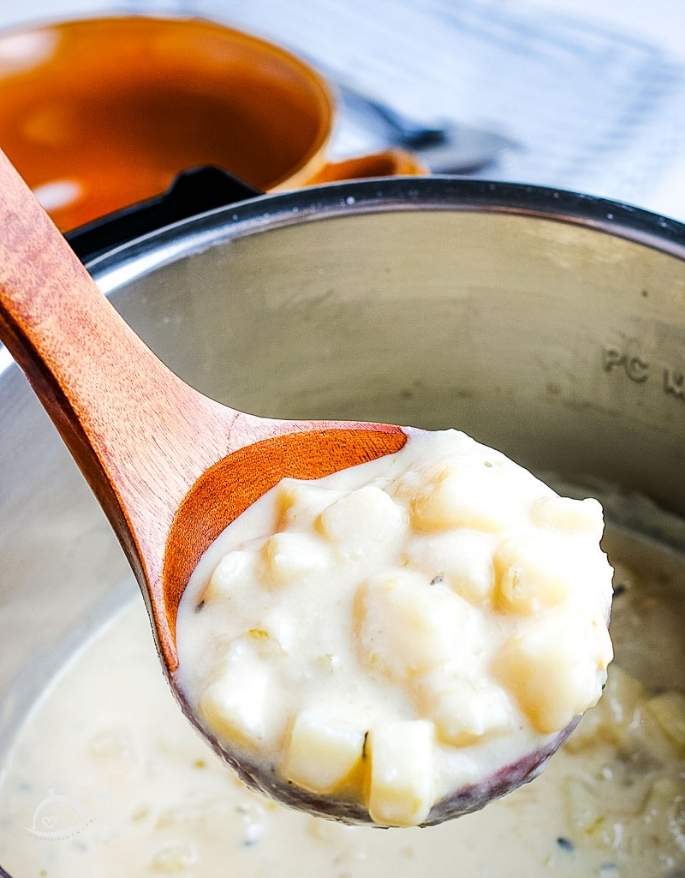 closeup view of a spoonful of instant pot loaded potato soup on a spoon above a pot of soup.