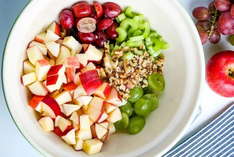 diced apples, halved grapes, chopped celery, and walnuts in a mixing bowl