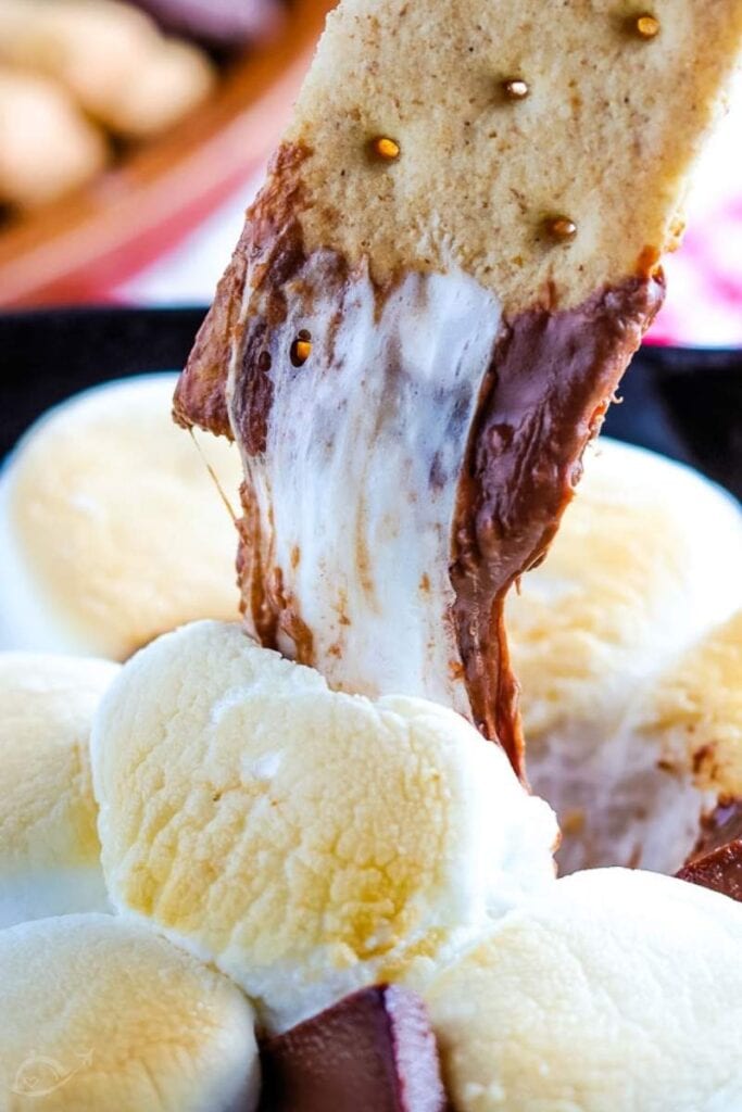 a graham cracker being dipped into the smores skillet dip