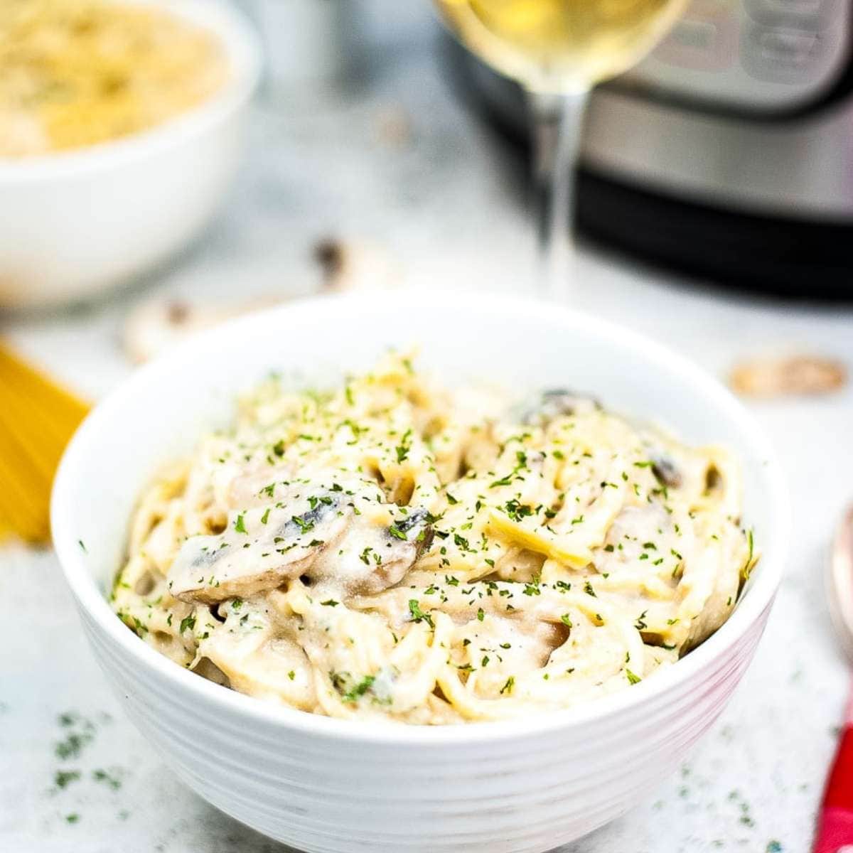 white bowl filled with cooked Instant Pot chicken tetrazzini garnished with parsley.