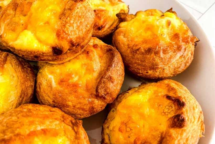 crescent roll quiche muffins topped with cheese in a white bowl