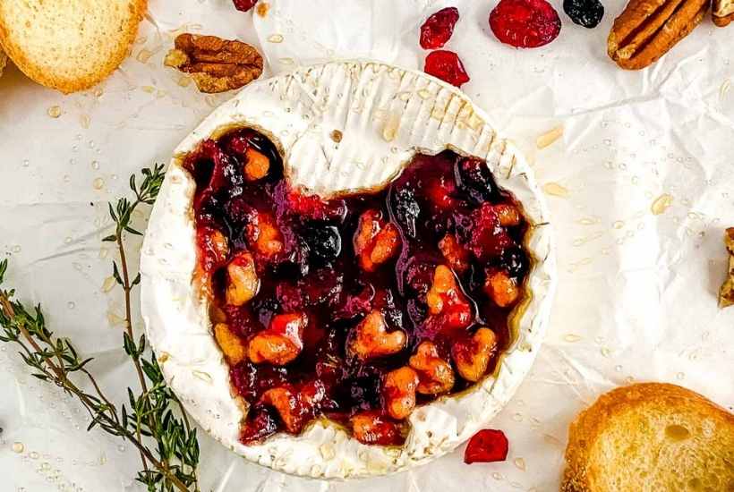 baked brie with a turkey cutout filled with cranberry sauce and walnuts