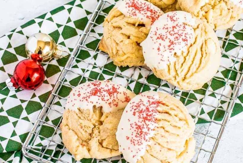 Peanut butter white chocolate chip cookies on a wire rack next to Christmas ornaments.