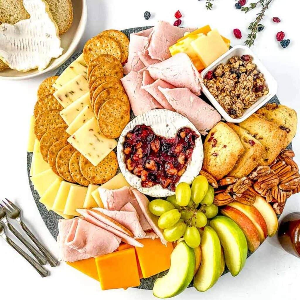 thanksgiving charcuterie board with cheese, crackers, fruits, next to mini forks