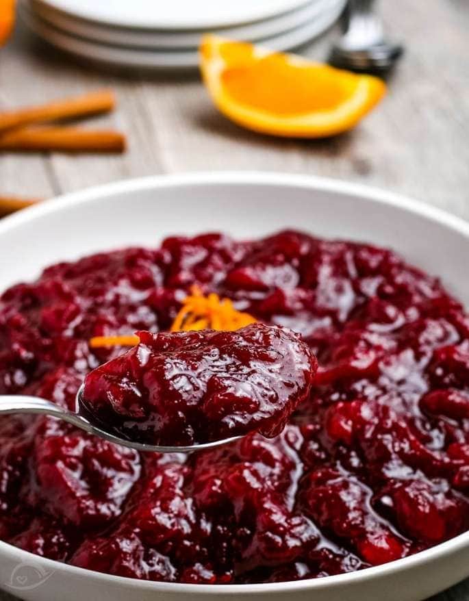 closeup of spoonful of cranberry sauce with bowl of sauce in the background