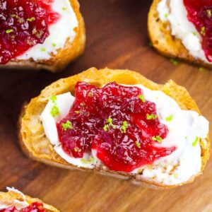 cranberry crostinis topped with cream cheese on cutting board