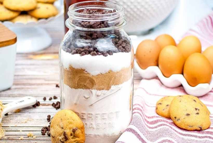 mason jar filled with layered cookie mix next to cookies and brown eggs