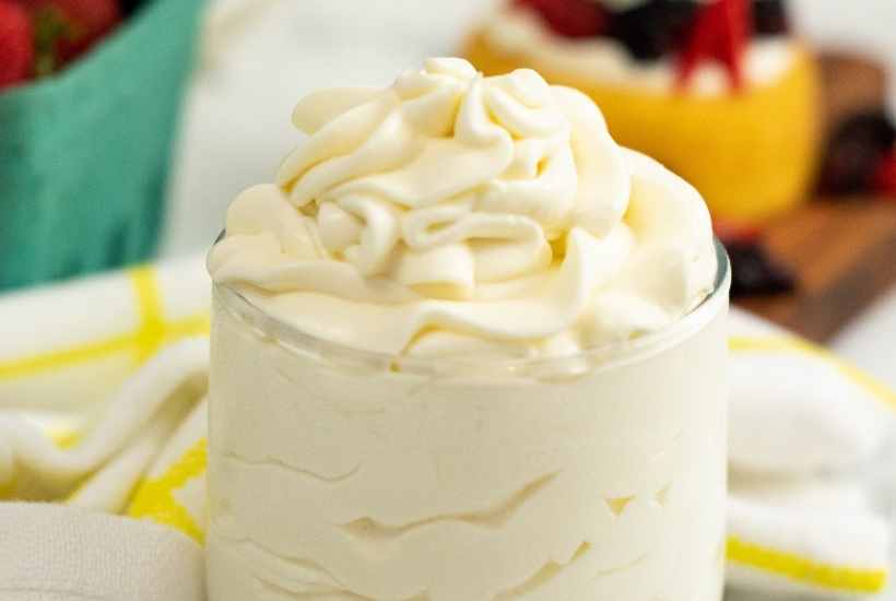 Close up view of cream cheese whipped cream frosting in a glass cup.