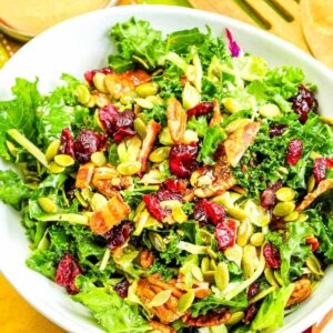 Kale and Brussel Sprout Salad with Cranberries with seeds and pecans in a white bowl